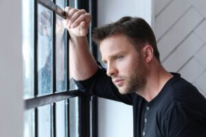 handsome-man-leaning-window-with-thoughtful-look