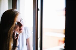 woman-talking-phone-near-window