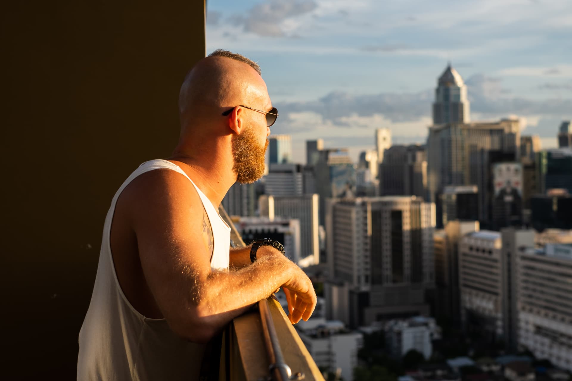 caucasian-handsome-bearded-brutal-man-enjoying-sunset-view-bangkok-city-from-high-floor
