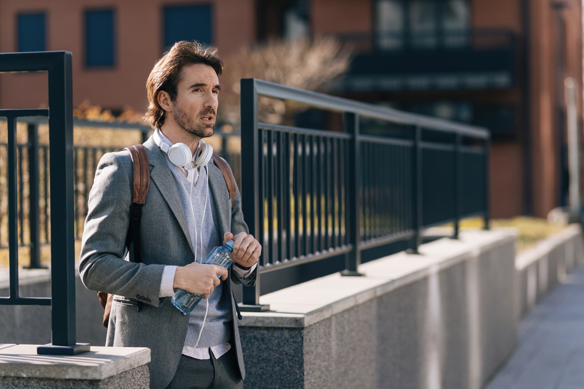 young-businessman-with-bottle-water-walking-city